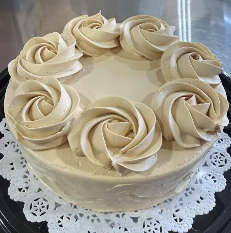 A cake with a white frosting on it showcasing mango tres leches.