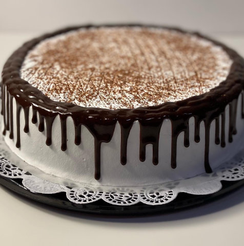 A cake with a frosting on top of it showcasing strawberry tres leches.
