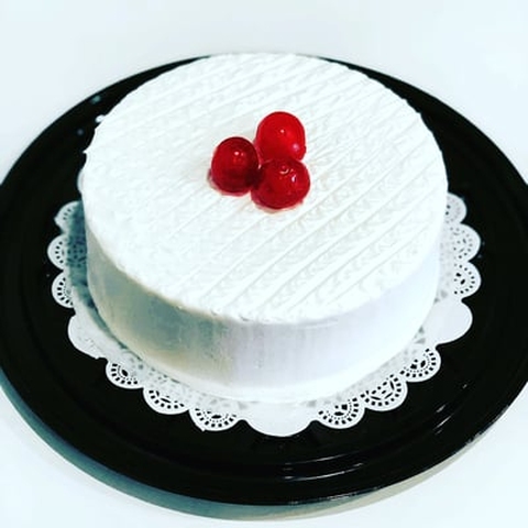 A white cake with strawberries on top showcasing custom cakes.