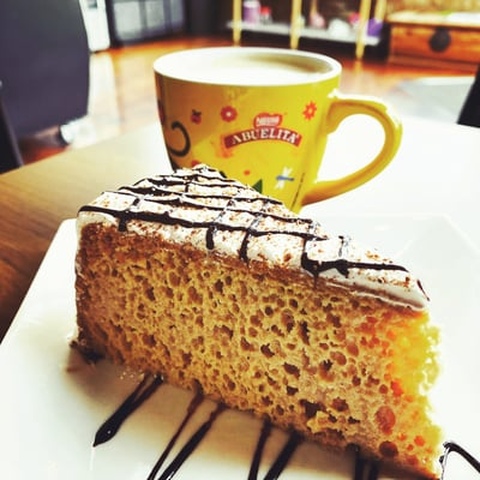 A piece of cake on a plate with a cup of coffee showcasing cake delivery.