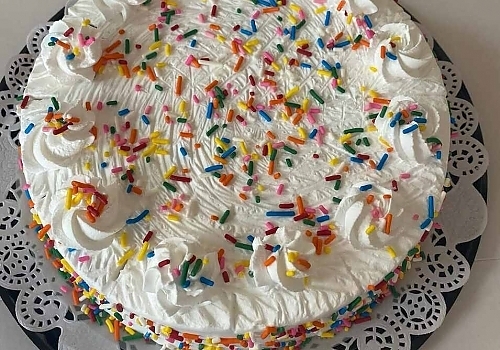 A white plate topped with a cake showcasing mango tres leches.