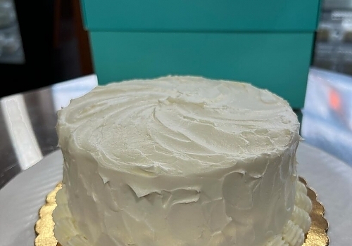 A cake with a large frosting on top showcasing wedding cakes.