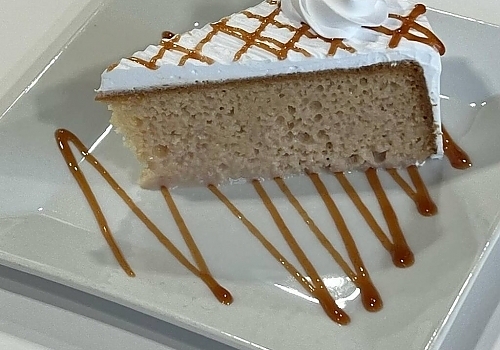 A piece of cake with frosting on a plate showcasing oreo tres leches.