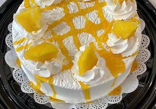 A cake with a frosting on top of it showcasing strawberry tres leches.