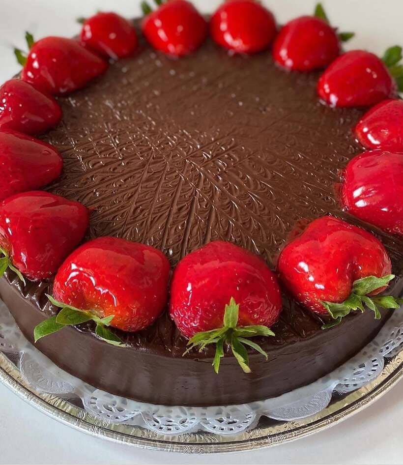A cake with strawberries and chocolate on it showcasing mango tres leches. 